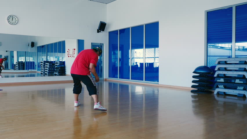Cool man in cap and sunglasses dancing the hip-hop in the gym