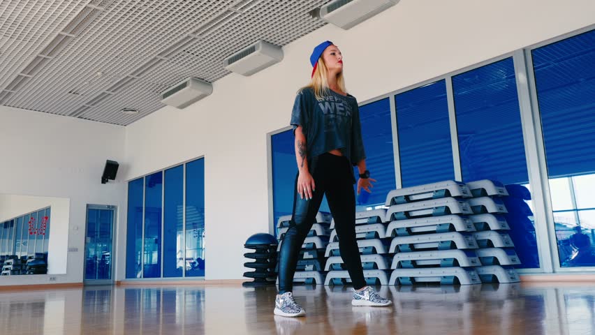 Pretty girl in cap dancing the modern dance in gym