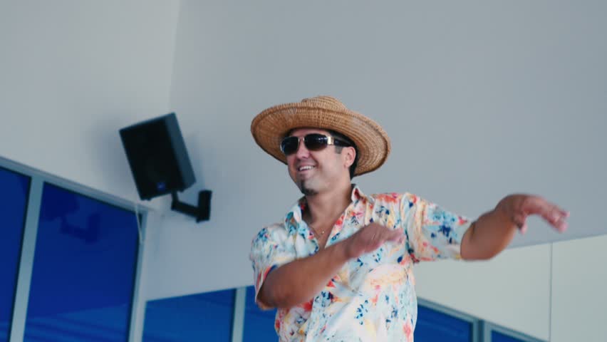 Smiling man in hat and sunglasses dancing in the gym