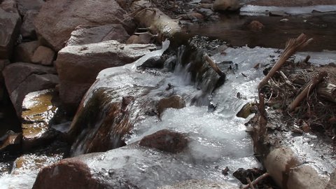 A log across a stream forms a partial dam and throws up spray that turns to ice as the cold water flows down from the Rocky Mountains in Colorado