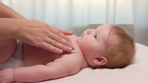 Mum massages baby's tummy and baby smiles