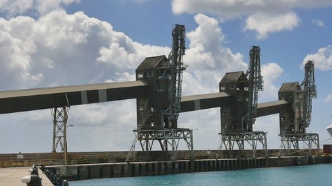 GEORGETOWN, BARBADOS-MARCH 2017: ZOOM-Sugar loading conveyors and towers at the Caribbean port of Georgetown, Barbados in the West Indies with beautiful white cloud blowing by in a clear blue sky.