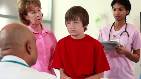 Pediatrician gives instructions to grandmother and nurse about diagnosis and care for boy patient.
