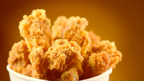 Rotation Bucket full of crispy fried chicken on brown background. UHD video footage. Ultra high definition 3840X2160 4K