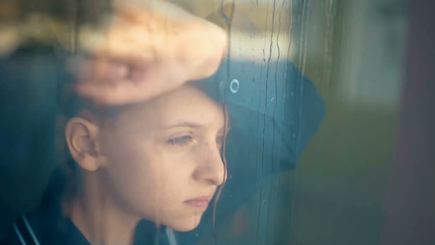 Sad unhappy kid standing near the window. Rain outside the window Royalty-Free Stock Footage #24962981