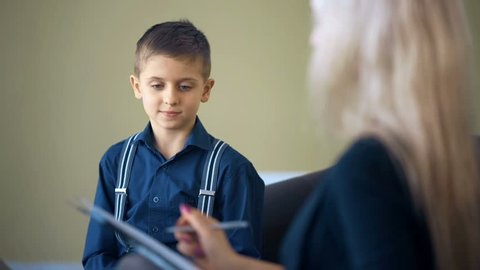 Therapy session classroom with boy listening the woman psychologist speech
