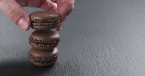 Slow motion of man hand stacking chocolate macarons on slate board, 4k 60fps prores footage