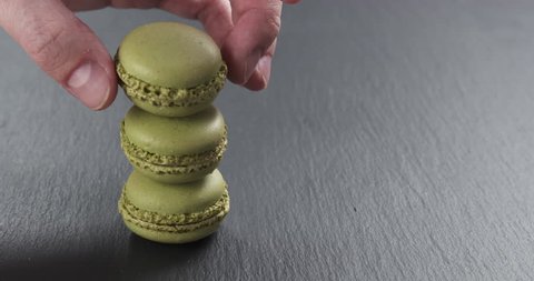 Slow motion of man hand stacking pistachio macarons on slate board, 4k 60fps prores footage