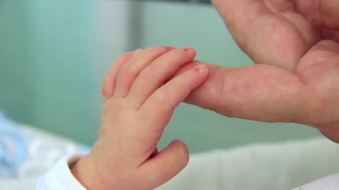 Mother and newborn daughter in maternity home. Hand in hand