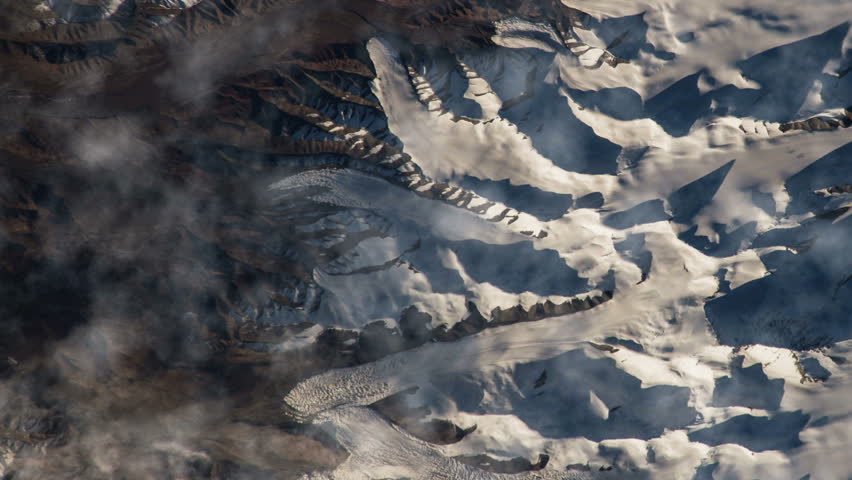 Flying over the earth on the ISS. Flying over the snow-capped mountains, aerial view from space.
