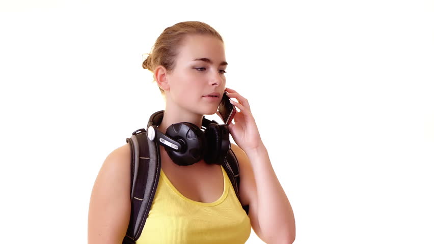 Pretty student with headphones and backpack speaks by cellphone 