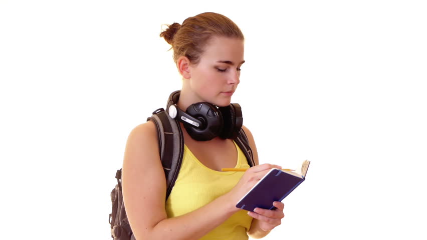 Pretty student with headphones and backpack writing note
