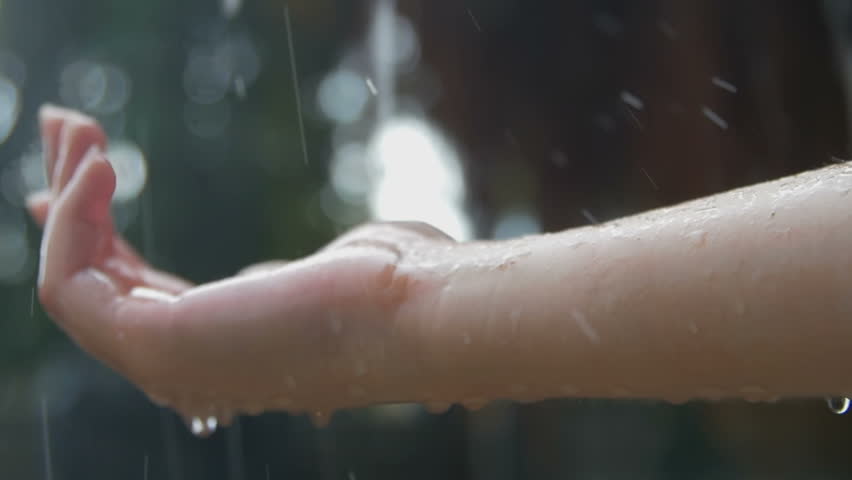 Women's hand covered in droplets of heavy rain in close-up