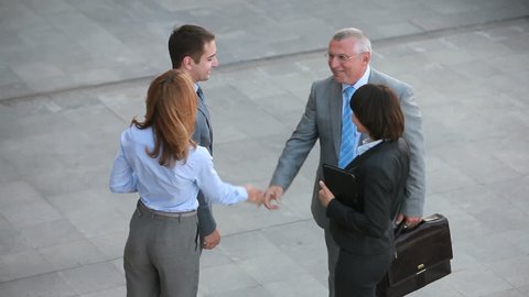 Positive business people shaking hands with their new partners and leading them away