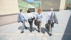 Confident business team walking steadfastly outside in urban surroundings