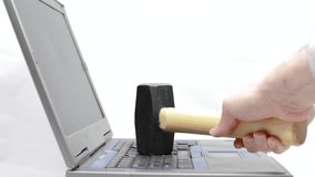 A handheld sledgehammer hammers against a laptop keyboard as seen from the side.