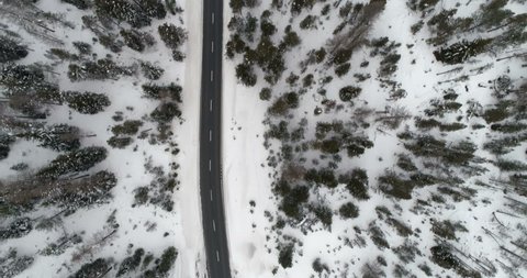 Aerial top view of asphalt road in high mountains. Winter forest with snow, foggy weather