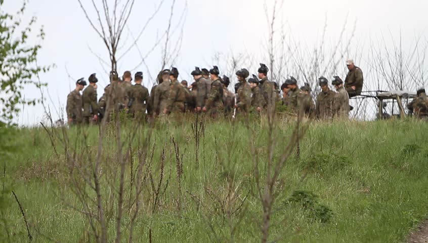  A group of men go through the forest, climb to the top and play paintball.. Shots from the battlefield of war.
