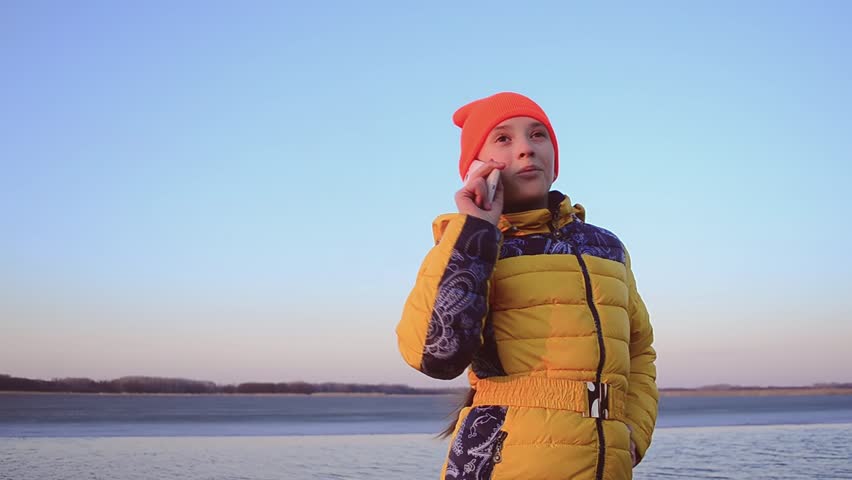 Teen girl talking on phone on background of bay