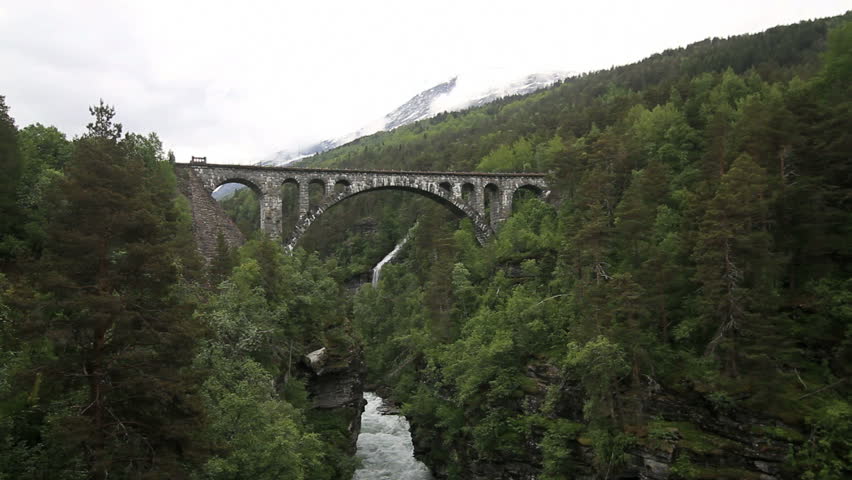 ROMSDAL, NORWAY, JUNE 20, 2012: Old railroad bridge crossing waterfall, commuter