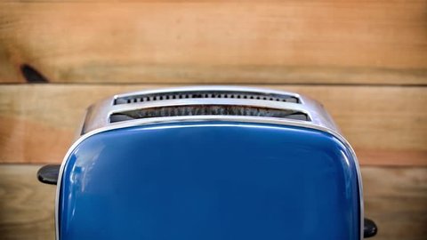 Seamless loop - Toast popping out of vintage blue toaster, wooden background, HD video
