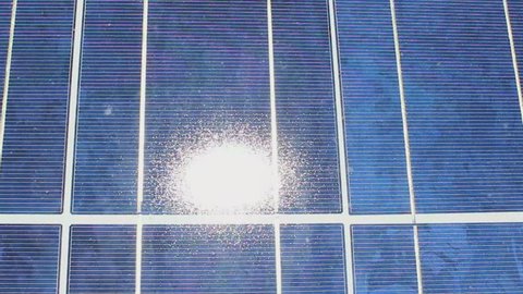 Sun glows powdery white on solar panels, pan left, close up. 1080p
