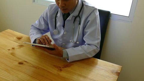 doctor in white lab coat using his tablet computer at work in medical office