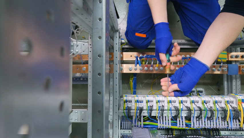 Factory electrician engineer installing cables with screwdriver, tighten the nut in electical box control cabinet into fuse box. Royalty-Free Stock Footage #25019468
