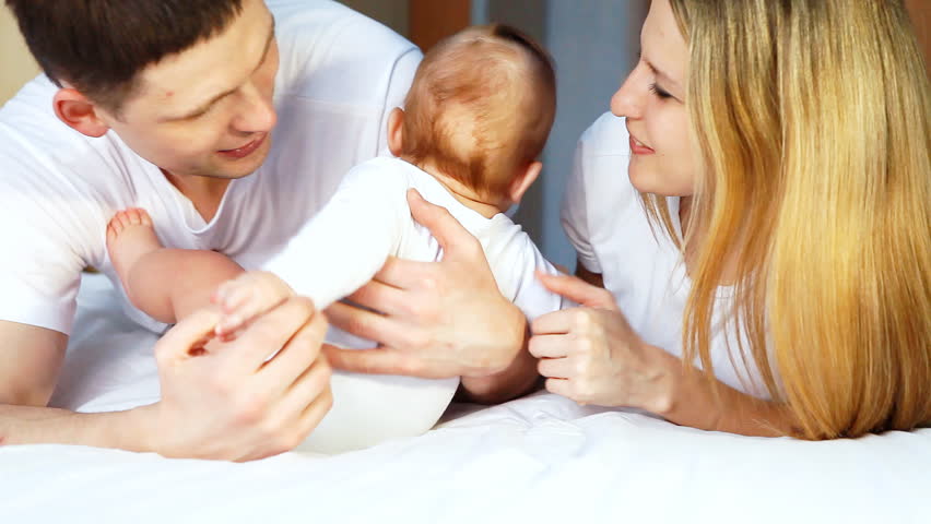 Happiness family: father, mother and baby playful on the bedroom