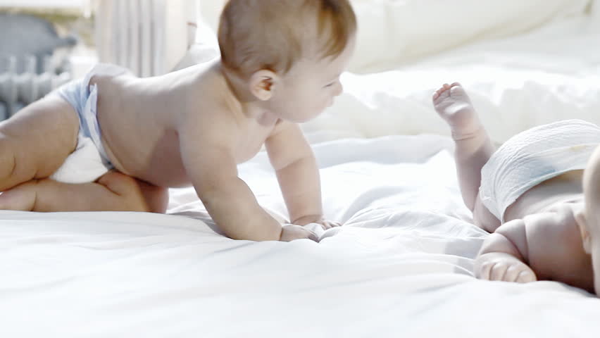 Two happiness babies having fun on the bed 