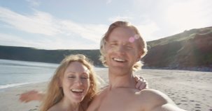 Happy couple having video on beach at sunset using phone smiling and spinning enjoying nature and lifestyle on vacation