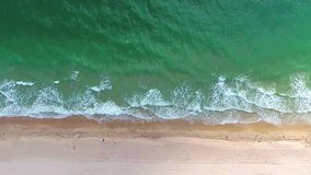 Tropical beach video loop showing seamless never ending footage with aerial bird eye view of green foaming ocean waves crushing against the coast line of Florida and overhead view of a seldom tourist