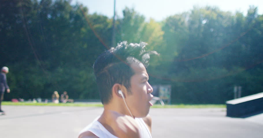 4K Young urban street dancer listening to music through earphones outdoors