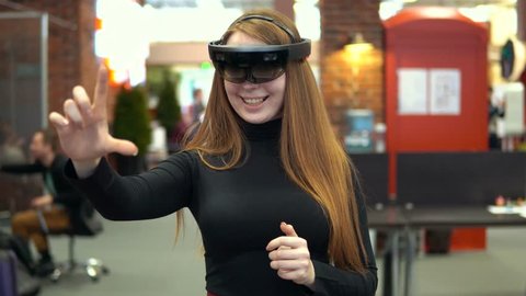 Attractive woman having fun uses head-mounted display in interior Hololens VR