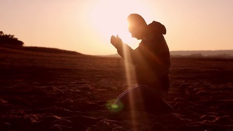 Silhouette of a man praying at sunset concept of religion