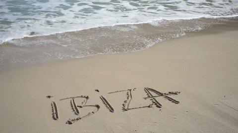 Ibiza written in sand beach washed away from waves, summer holiday concept.