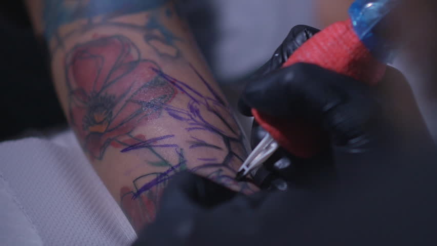 Professional tattoo artist makes a tattoo on a young girl