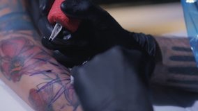 Professional tattoo artist makes a tattoo on a young girl's hand in slow motion. Tattoo artist make tattoo at the studio,close up