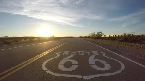 San Bernardino County, California, USA - March 11, 2017:  Route 66 pavement sign sunset driving shot with passing train.