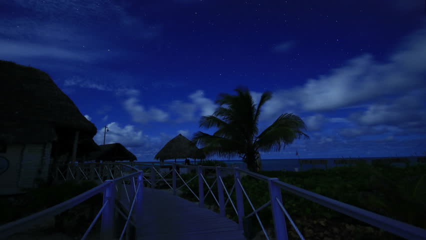 Beach footpath with stars and clouds moving in night sky under moonlight, on an island in Caribbean Sea in Cayo Santa Maria, Cuba