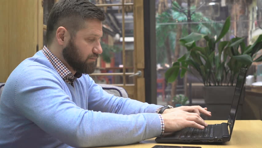 Focused man working, writing on laptop computer, in pub, profile, steadicam shot Royalty-Free Stock Footage #25040774