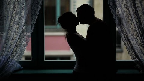 Passionate Couple is Kissing and Hugging in the Darkness. Silhouette of the Man and Woman in Love near the Window.
