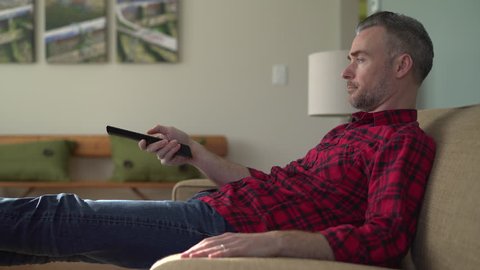View of a man laying on couch channel surfing