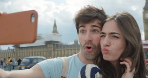 Tourist couple taking selfie in front of Big Ben smartphone in city sharing lifestyle photo enjoying holiday European vacation travel adventure London