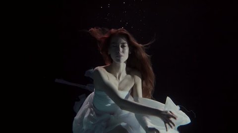 young woman swimming underwater in a white dress like a fairy tale