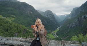 Beautiful woman taking selfie photo using smartphone outdoors Girl sharing photograph on social media with mobile phone enjoying Norway vacation travel adventure