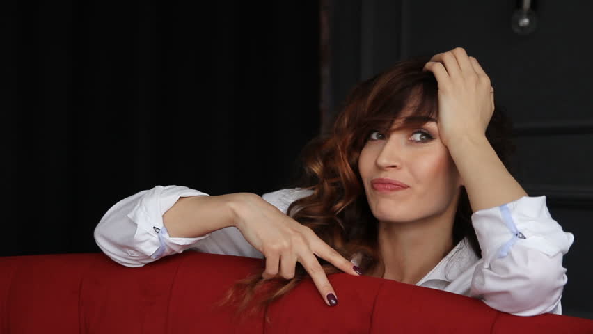Happy model smiling and posing behind red sofa