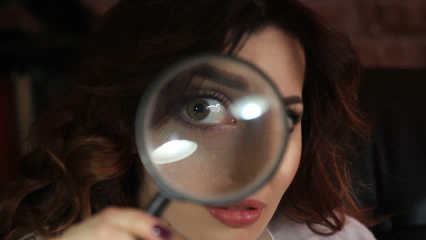 pretty brunette woman puts a magnifying glass to eyes and mouth showing teeth Royalty-Free Stock Footage #25063022