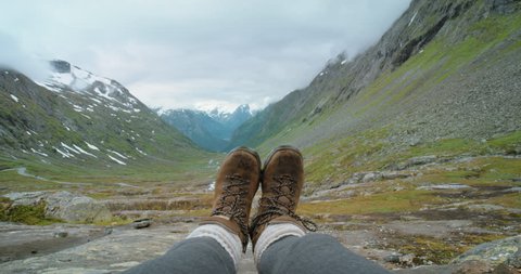 Close up hiking boots of Independent Woman traveller on top of mountain valley looking at view Hiker girl dangling feet over enjoying vacation travel adventure nature Norway