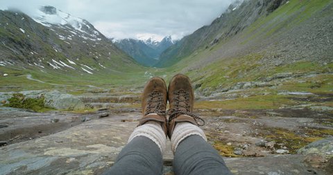 Close up hiking boots of Independent Woman traveller on top of mountain valley looking at view Hiker girl dangling feet over enjoying vacation travel adventure nature Norway